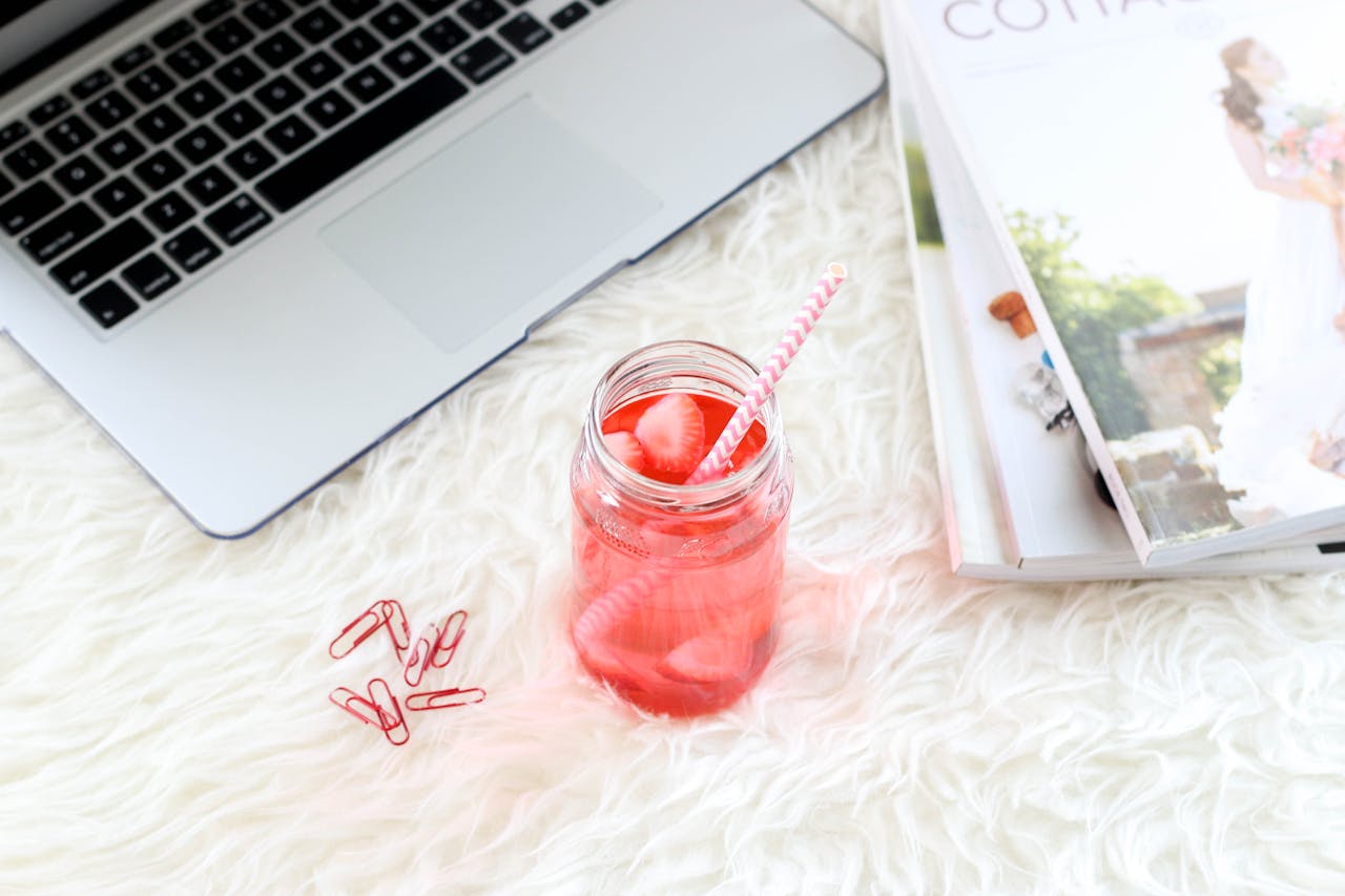 heros-img A cozy workspace setup with a refreshing strawberry drink, laptop, and magazines.