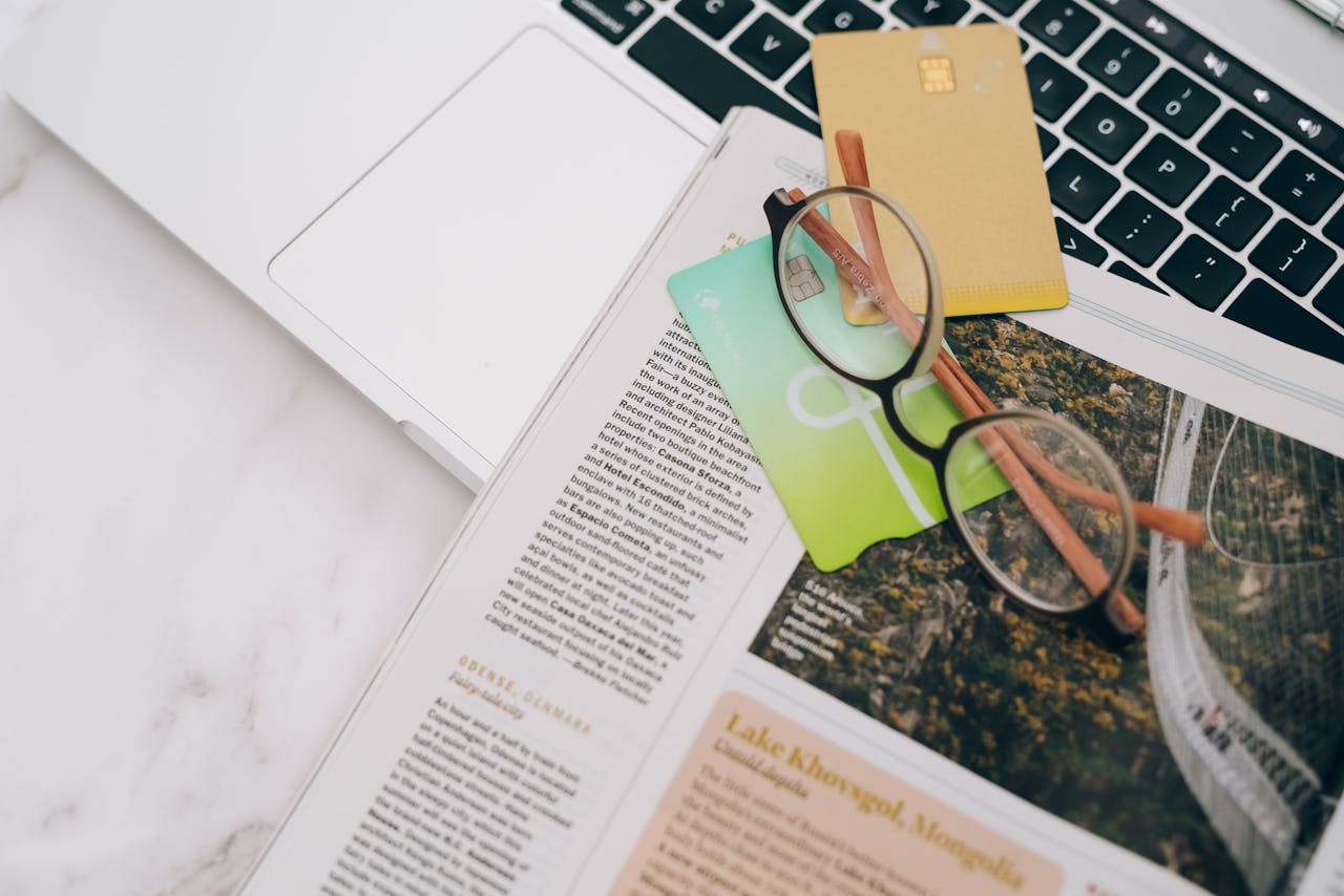 our-story Eyeglasses resting on a magazine beside a laptop and credit cards, indoors.